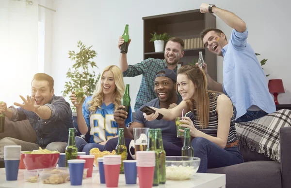 Friends watching the big game together on a couch.